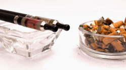 e-cigarettes next to a cigarette butts in an ashtray