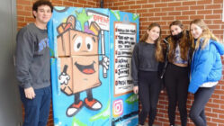Teens standing with a free food fridge