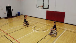 two people in wheelchairs play basketball