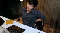 Young man with an aching back at his desk