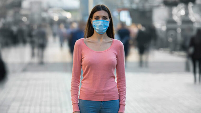 A young girl wearing a COVID mask feeling alone in public.