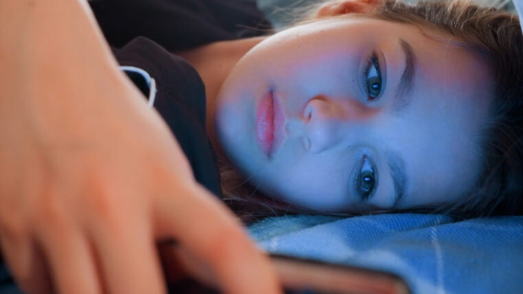 A tired young girl on her phone in bed