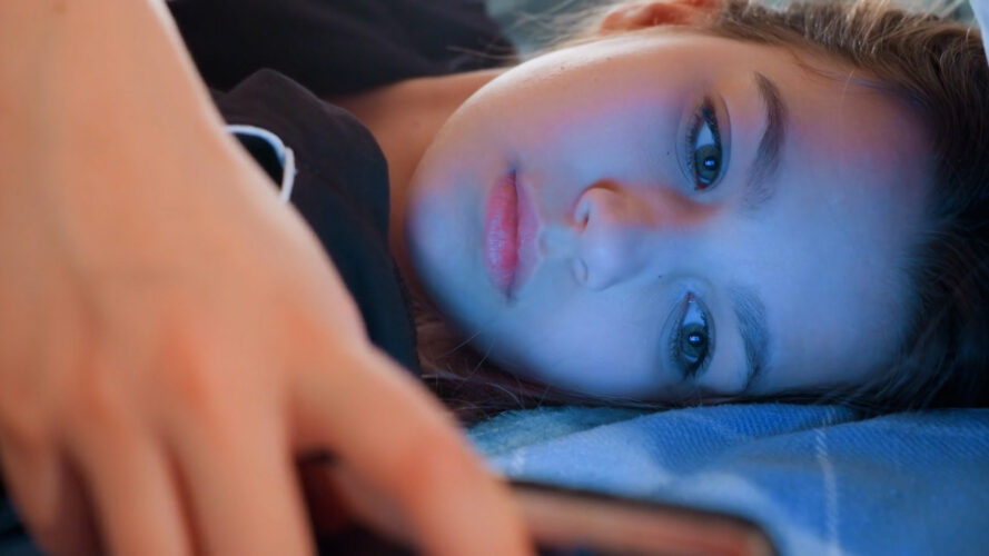 A tired young girl on her phone in bed